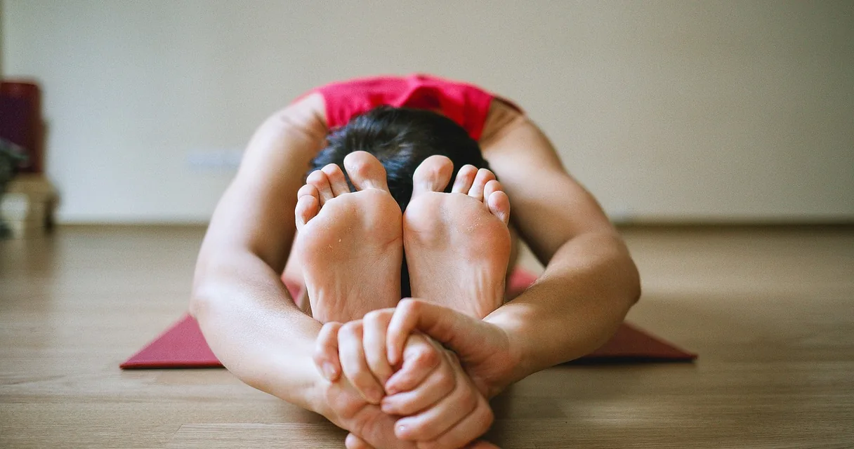 Mulher jovem fazendo alongamento no tapete de uma sala de exercícios